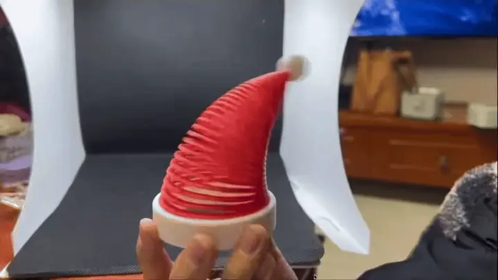 Animation of a hand holding the slinky Santa hat as it sways and straightens