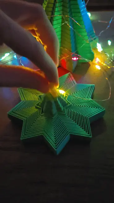 Animation of a hand pulling the yellow star so the green fidget rises into a tree, then pressing it flat