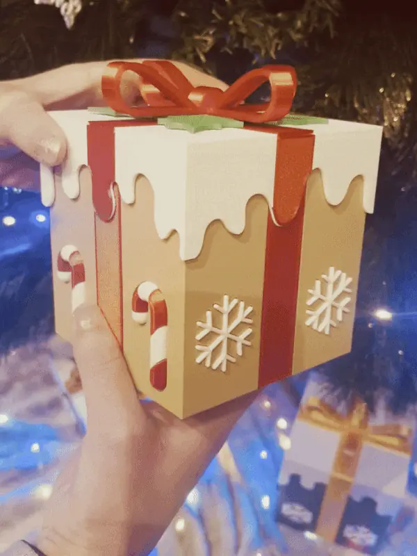 A hand lifting the lid off the iced present box
