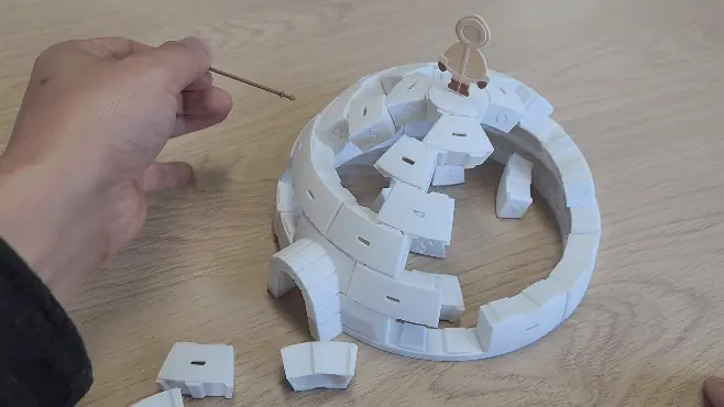 Animation of a hand pushing a numbered ice brick out of a half-built igloo with a stick